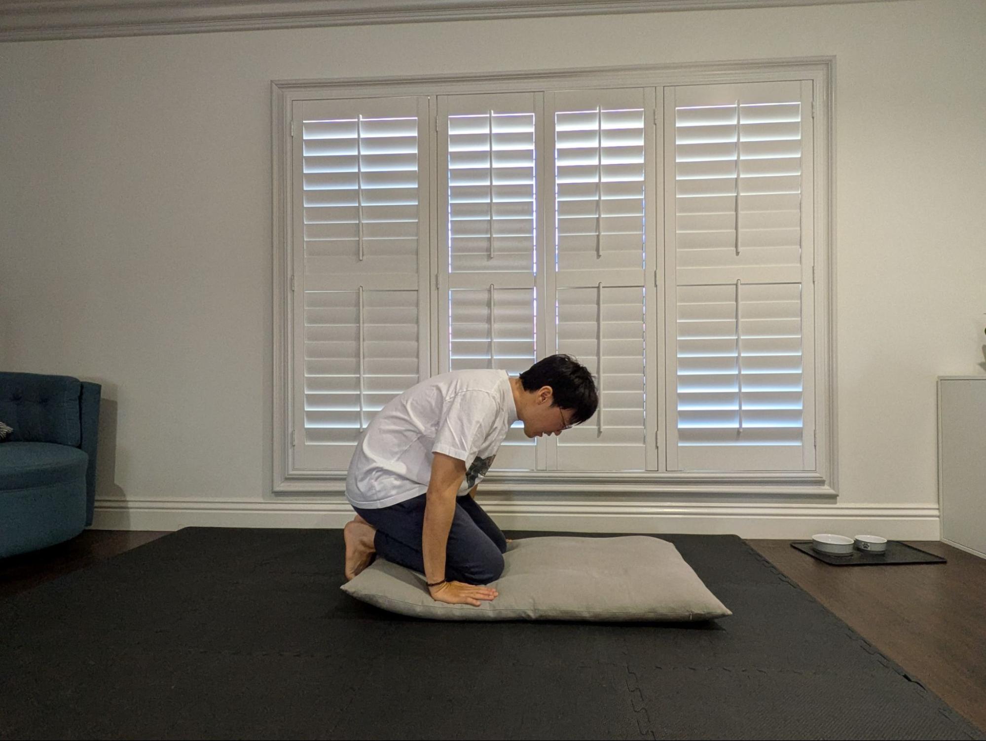 Kneeling with hands placed on the cushion, feet crossed